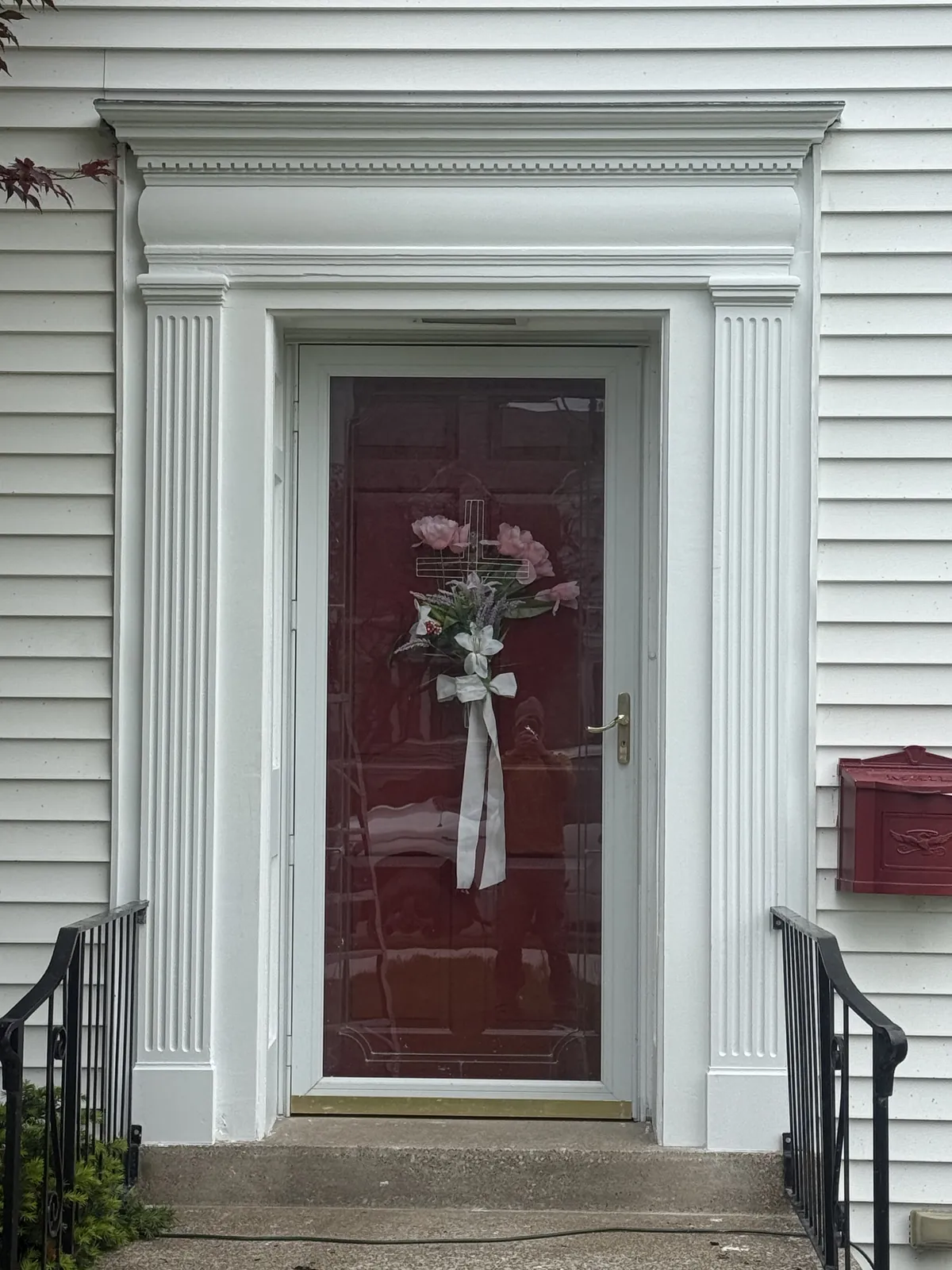 Restored entry with fluted pilasters, painted millwork, and burgundy door