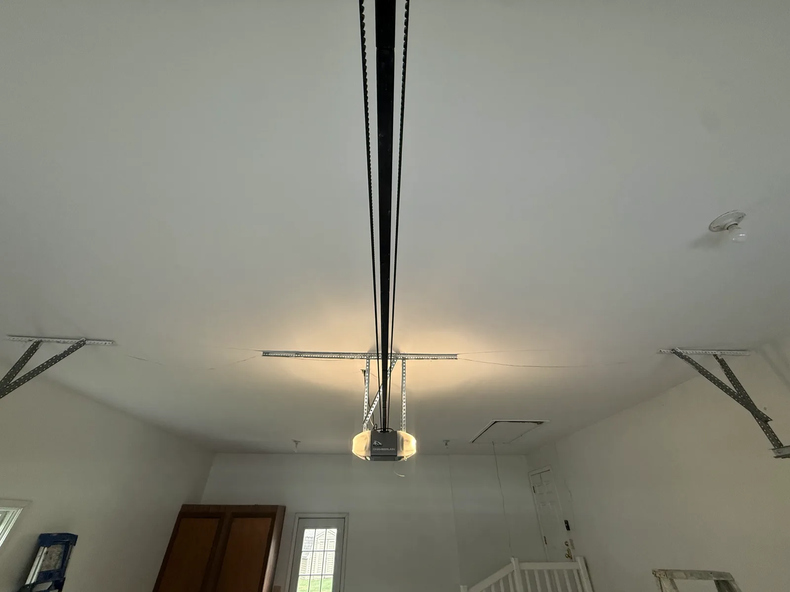 Finished garage after drywall ceiling replacement — full space with clean ceiling, opener, and walls