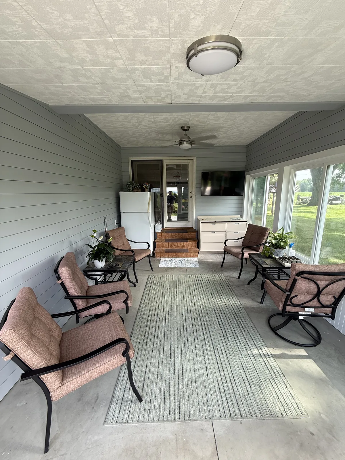 Finished sunroom remodel — full room with seating, shiplap, and yard views