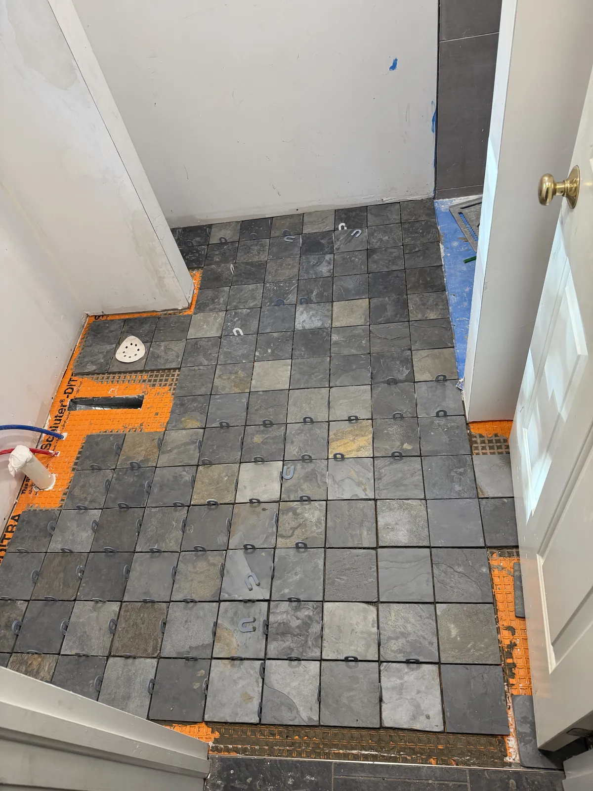 Slate floor tile set with leveling clips before grout.